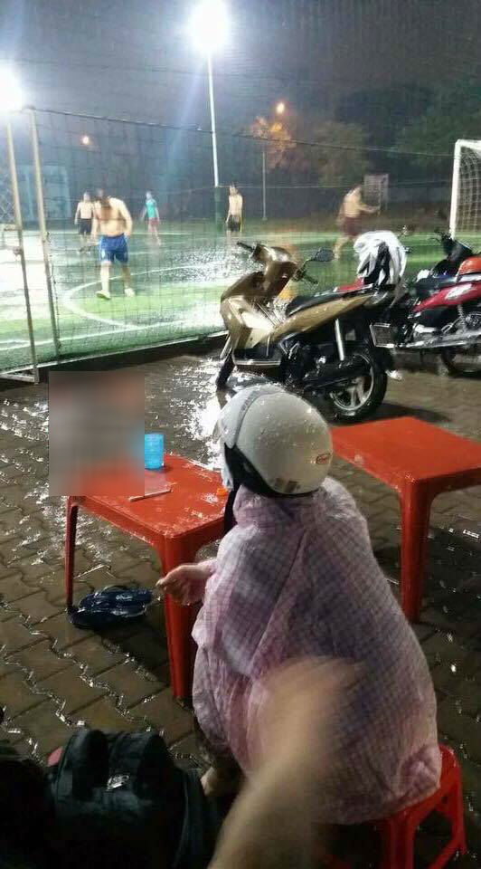vợ cổ vũ chồng đá bóng dưới mưa