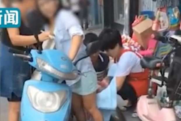 Sản phụ trẻ chuyển dạ sinh con ngay giữa phố với chiếc xe máy bên cạnh. Ảnh: Weibo