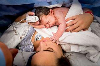 Em bé vừa chào đời đã thích thú vươn tay sờ mặt mẹ