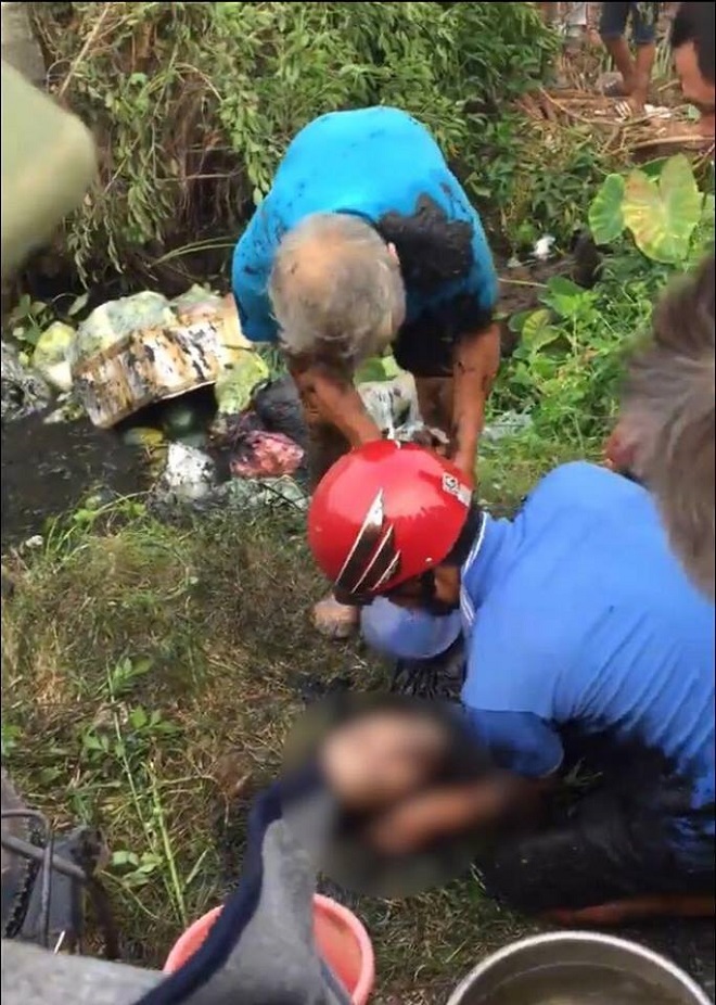 Người phụ nữ chết thảm sau khi lao xuống mương nước thải. Hai người áo xanh được cho là bố đẻ và chồng nạn nhân