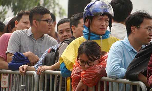 ​Một cô gái vẫn mặc nguyên áo mưa, tranh thủ chợp mắt giữa dòng người đông đúc